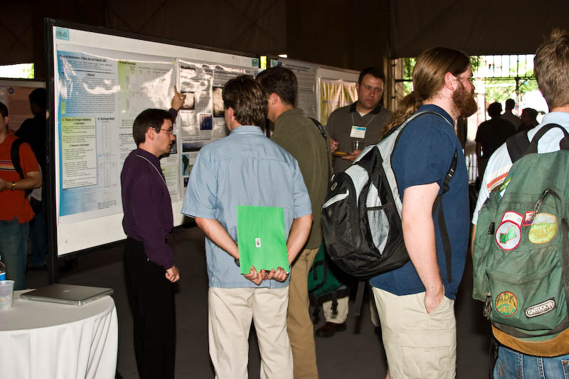 Jeremy Riousset (PSU, 1st place winner) explains his poster to the judges(Dan Marsh) with green folders