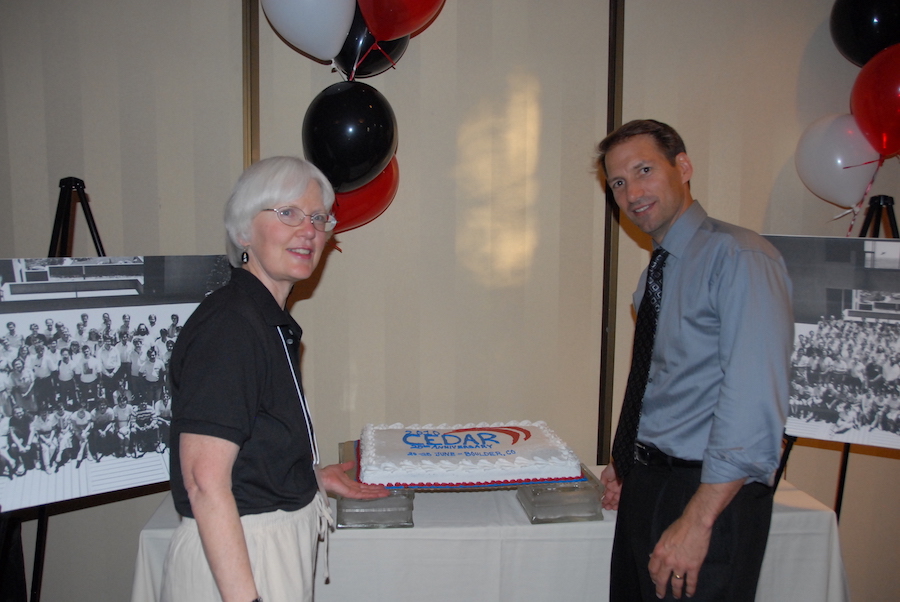 Barbara Emery (NCAR organizer) and Jeff Thayer (U CO chair) in front of the 1990 group photos and the cake with the 25th anniversary logo