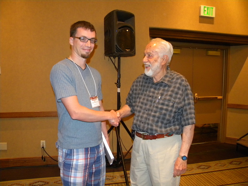 Tutorial Speaker Andy Nagy gives a copy of the 2007 ISSI conference book 'Comparative Aeronomy' he edited to the graduate student with the best question, William Archer of the University of Calgary in Canada.