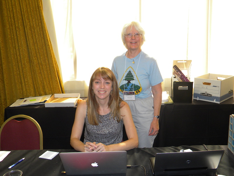 Barbara Emery (local organizer, HAO/NCAR) stands behind Kendra Greb (VSP/UCAR) at the registration desk at the Millennium Hotel.