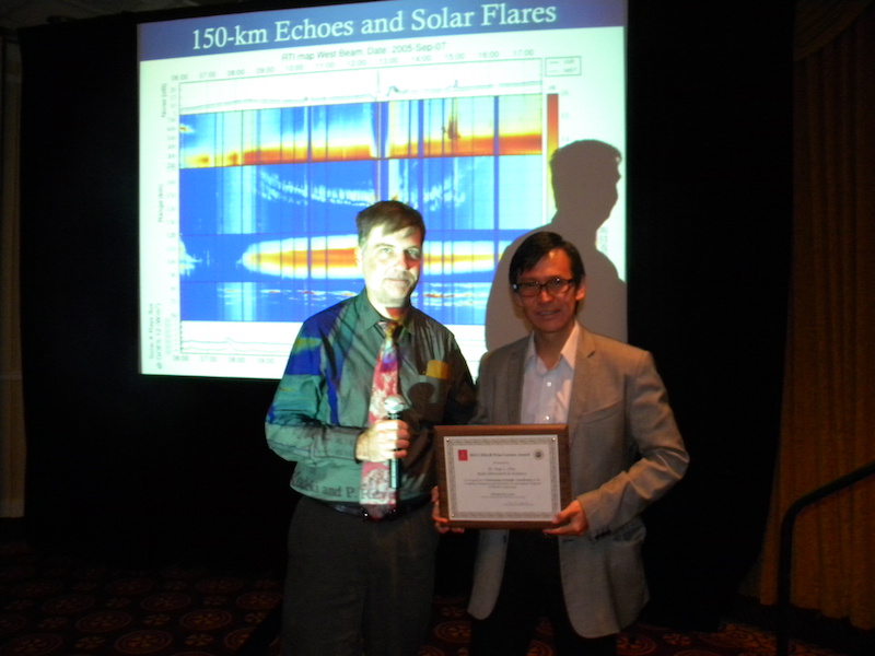 24th CEDAR Prize recipient Jorge (Koki) Chau (Jicamarca Radio Observatory, Peru) receives the CEDAR Prize award plaque from CEDAR Chair Dave Hysell (Cornell) in front of one of his slides on 150-km echoes on Monday 24 June 2013.